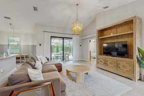 Ein modernes Wohnzimmer mit Sofa, Couchtisch, Fernseher und Holzschrank.