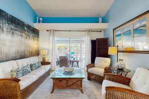 A living room with a sofa, chairs, a coffee table, and a painting on the wall. - Waterfront home with private, heated pool, dock, and lanai (Cape Coral)