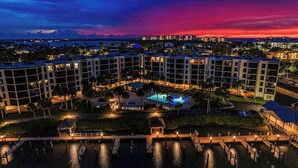 A hotel with multiple buildings, a swimming pool, and a dock area. - Water view condo with shared pool, panoramic balcony views, and WIFI (Marco Island)