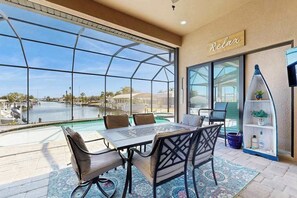 A terrace with a table and chairs, a glass enclosure, and a sign that reads 'Relax.' - Ultimate waterside retreat with private dock, lanai, pool & spa, BBQ and WiFi (Port Charlotte)