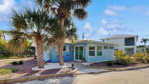 A two-story house with a blue exterior, a front porch, and a palm tree. - Ground floor, dog-friendly home with access to beautiful Gulf beaches and trails (Sanibel)