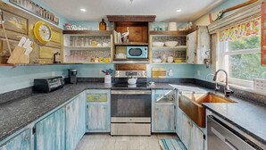 A kitchen with a microwave, stove, sink, and various utensils on shelves. - Ground floor, dog-friendly home with access to beautiful Gulf beaches and trails (Sanibel)