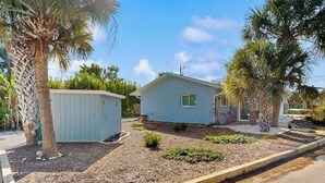A single-story house with a small front yard, a wooden deck, and a palm tree. - Ground floor, dog-friendly home with access to beautiful Gulf beaches and trails (Sanibel)
