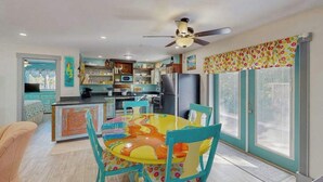 A kitchen with a dining area, a ceiling fan, and a window with curtains. - Ground floor, dog-friendly home with access to beautiful Gulf beaches and trails (Sanibel)