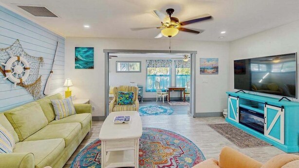 A living room with a sofa, coffee table, TV, and decorative wall art. - Ground floor, dog-friendly home with access to beautiful Gulf beaches and trails (Sanibel)
