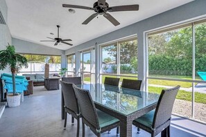 A spacious patio with a glass-top table and wicker chairs, large windows, ceiling fans, and a view of the outdoors. - 6BR Resort-Style Compound | Pool & Spa | Sleeps 12 | 2 Homes in One | Near Beach (Bonita Springs)