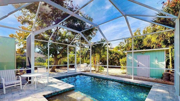 A pool area with a covered section, seating, and a small shed. - Dog-friendly duplex with outdoor living - walk to beach & downtown (Venice)