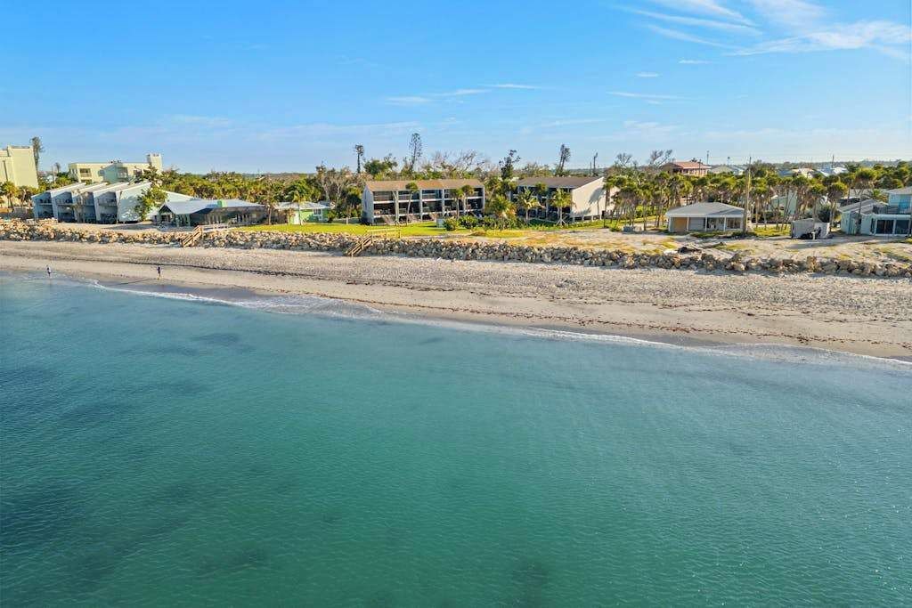 A coastal hotel with a beach view, multiple buildings, and a clear sky.