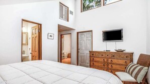 A bedroom with a large bed, a wooden dresser, a television, and a chair. - Chic Home With Private Pool, Hot Tub & Covered Lanai - Snowbirds Welcome (Sanibel)