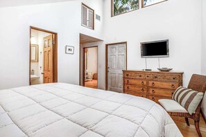A bedroom with a large bed, a wooden dresser, a television, and a chair. - Chic Home With Private Pool, Hot Tub & Covered Lanai - Snowbirds Welcome (Sanibel)