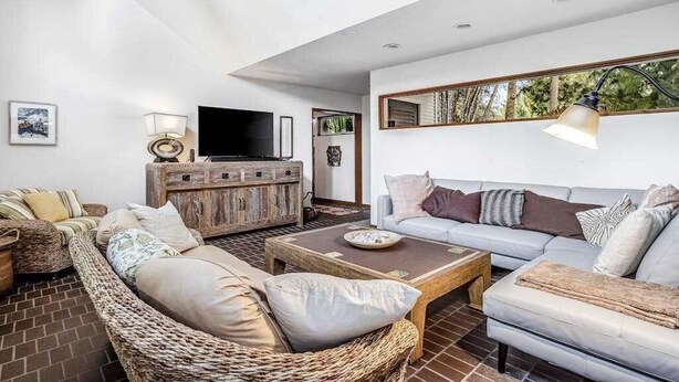 A living room with a sofa, a coffee table, a television, and a fireplace. - Chic Home With Private Pool, Hot Tub & Covered Lanai - Snowbirds Welcome (Sanibel)
