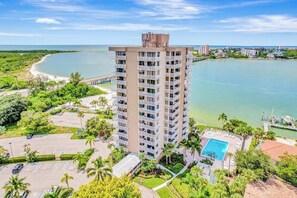 A high-rise hotel with a pool, surrounded by greenery and a beach. - Waterfront condo with private beach area, pool, hot tub, grills, & balcony (Fort Myers)