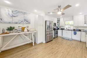 A modern kitchen with white cabinetry, stainless steel appliances, and a marble backsplash. - Spacious & beautiful home with fast WiFi, central AC, patio, and W/D (Naples)