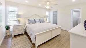 Ein Schlafzimmer mit Bett, Nachttischen, Deckenventilator und einer Tür.
