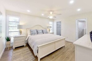 A bedroom with a bed, bedside tables, a ceiling fan, and a door. - Spacious & beautiful home with fast WiFi, central AC, patio, and W/D (Naples)