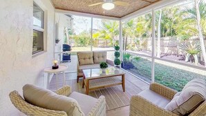 Ein geräumiges Zimmer mit Deckenventilator, großen Fenstern und Blick auf einen Garten.