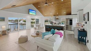 Amplia sala de estar con techo alto, cocina y balcón con vista al puerto deportivo.