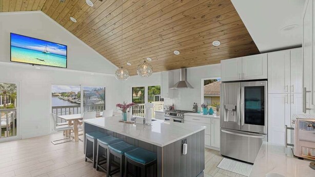 Una cocina moderna con una isla grande, electrodomésticos de acero inoxidable y techo de madera.