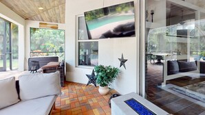 Un intérieur moderne avec un canapé, une plante en pot, un téléviseur et une porte vitrée donnant sur l’extérieur.