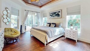 Une chambre à coucher avec un plafond en bois, un lit, une chaise, une table de chevet et une fenêtre avec des rideaux.