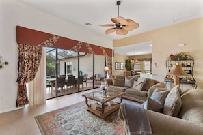 A spacious living area with a sofa, coffee table, and a ceiling fan. - Lakeside paradise with private pool, tennis courts, and more (Naples)