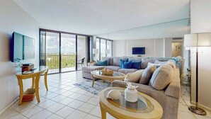 A modern living room with a sofa, coffee table, and TV. - Waterfront, gulf view condo by beach with pool, dock & balcony (Marco Island)