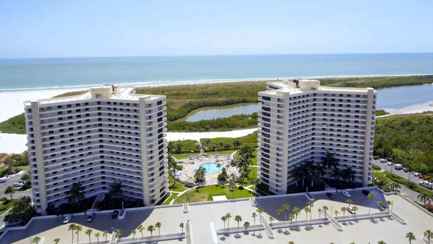 Two high-rise buildings with a pool and beach view. - Waterfront, gulf view condo by beach with pool, dock & balcony (Marco Island)