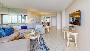 A modern living room with a sofa, coffee table, and TV. - Waterfront, gulf view condo by beach with pool, dock & balcony (Marco Island)