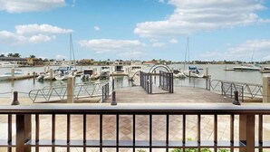 Uma marina com barcos atracados, uma entrada com portão e céu claro.