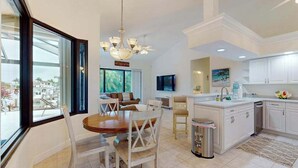 A spacious kitchen with a dining area, large windows, and a view of the outdoors. - Canal-front home with private pool, pool spa, dock, boat access, grill, gym, W/D (Marco Island)