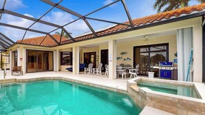 A pool area with a covered patio, chairs, and a grill. - Canal-front home with private pool, pool spa, dock, boat access, grill, gym, W/D (Marco Island)