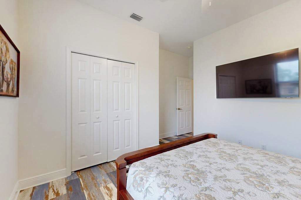 A bedroom with a bed, a wardrobe, and a wall-mounted TV.