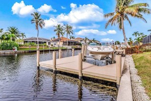 A marina with a dock, boats, and palm trees.