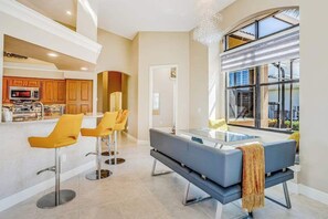 A modern kitchen with wooden cabinets, a built-in microwave, and a bar area with yellow chairs. - Canal-front home with fast WiFi, pool, & lanai - near beach (Marco Island)