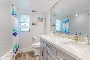 A bathroom with a white sink, a large mirror, a toilet, and a shower curtain with a blue and white pattern. - Waterfront Home with Private Dock & Enclosed Lanai - Near Residence Beach (Marco Island)