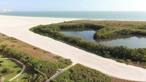Paisaje costero con playa de arena, masa de agua y vegetación densa.
