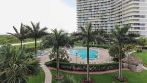 Un hotel con una piscina grande, palmeras y una fachada de edificio curva.