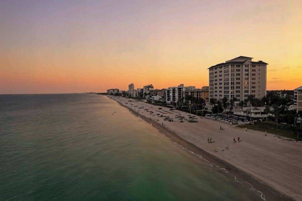 A coastal hotel with a beach view, multiple floors, and a prominent building on the right.