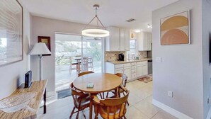 A modern kitchen with white cabinets, a dining area with a round table and chairs, and a large window providing natural light. - Dog-Friendly, Snowbird-Ready Florida Escape – Near Beaches & Golf (Port Charlotte)