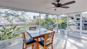 A dining area with a table and chairs, a ceiling fan, and large windows with a view of the outdoors. - Dog-Friendly, Snowbird-Ready Florida Escape – Near Beaches & Golf (Port Charlotte)