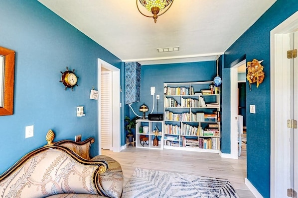 A room with a blue wall, a bookshelf, a patterned rug, and a decorative ceiling light.