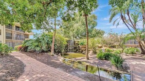 Ein angelegter Garten mit einem kleinen Teich, einem Wasserfall und einem gepflasterten Weg.