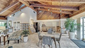 Ein geräumiger Innenbereich mit hohen Decken, einem Esstisch, Stühlen, einer Couch und Topfpflanzen.