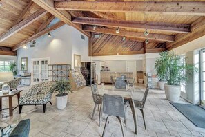 Ein geräumiger Innenbereich mit hohen Decken, einem Esstisch, Stühlen, einer Couch und Topfpflanzen.