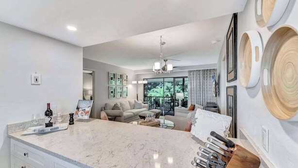 Eine moderne Küche mit Marmorarbeitsplatte, ein Essbereich mit einer Couch und ein Wohnzimmer mit einem Chandelier.
