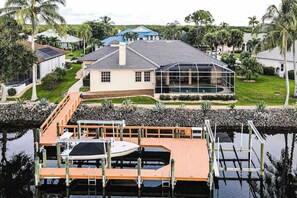 A house with a swimming pool, dock, and surrounding greenery. - Upscale waterfront home with private dock, saltwater pool, lanai, grill, & W/D (Naples)