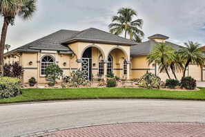 A two-story house with a symmetrical facade, arched windows, and a central entrance. - Upscale waterfront home with private dock, saltwater pool, lanai, grill, & W/D (Naples)