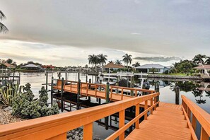 A marina with docked boats, a wooden pier, and houses in the background. - Upscale waterfront home with private dock, saltwater pool, lanai, grill, & W/D (Naples)