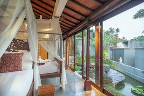 A bedroom with a canopy bed, a view of a garden, and a water feature. - private 4-bedroom villa with Infinity pool in peaceful Ubud (ubud)