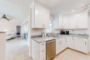 A modern kitchen with white cabinets, a dishwasher, and a granite countertop. - Waterfront home with an enclosed pool, outdoor kitchen, and grill - dog-friendly (Port Charlotte)